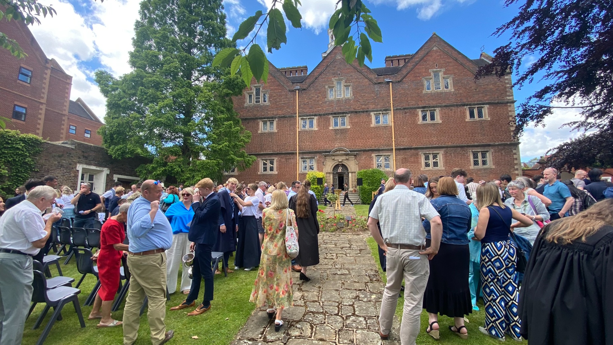 families gather for prizegiving in founders garden, with the 17th century founders building in the background on a sunny june morning